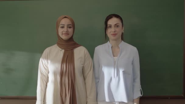 Female Teacher Hijab Female Colleague Looking Camera Classroom Arms Front — Vídeos de Stock
