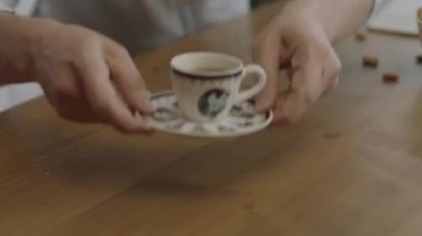 A man serving coffee to his wife or friend at home. Man serving in slow motion. Coffee break. Close-up hands of man trying not to spill while serving Turkish coffee to guest.