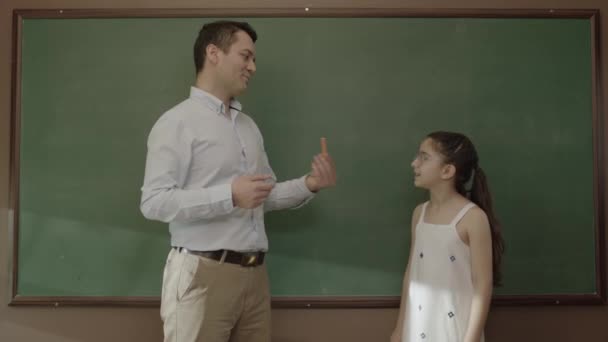 在教室的黑板上 年轻的老师在教女生数学 一个理想主义教师的画像 他想帮助他的学生准备考试并成功 成功的教师 — 图库视频影像