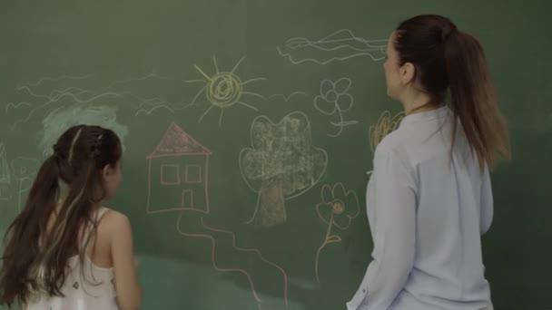 教室の黒板に女の子と女教師が絵を描き 子供の遊び場で女教師と遊んで学ぶ 教師と学生の肖像 — ストック動画