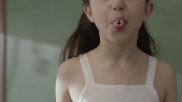 一个女孩的嘴是遗传自她的父母的遗传特征 她的舌头卷曲成U形的宏 一个小女孩伸出舌头 抬起头来的特写画面 — 图库视频影像