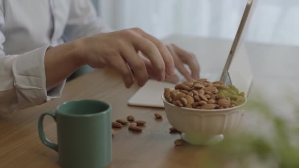 Freelance Mies Juo Kahvia Syö Paahdettuja Manteleita Hasselpähkinöitä Evästeitä Työskennellessään — kuvapankkivideo