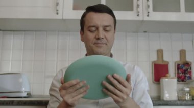 In the kitchen of his house, the young man who loves food licks his plate. Fine dining concept. Hungry man licking an empty plate.