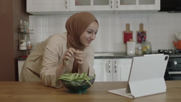 Женщина Хиджабе Смотреть Рецепт Смешное Видео Планшетном Компьютере Подготовке Пищи — стоковое видео