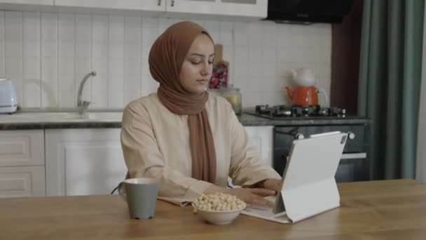 Young Woman Hijab Working Remotely Tablet Computer Woman Eats Roasted — Vídeo de stock