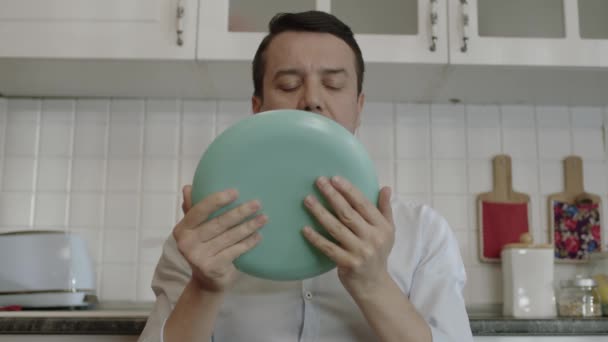彼の家の台所で 食べ物を愛する若い男は彼の皿をなめる 素晴らしい食事のコンセプト 空腹の男なめる空のプレート — ストック動画