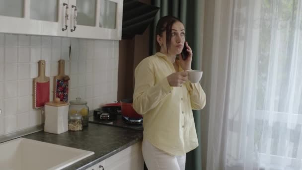 Young Mother Preparing Food Kitchen Talking Cell Phone While Drinking — Stock video