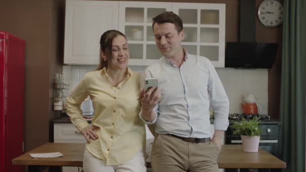 キッチンのダイニングテーブルでスマートフォンを使用して幸せなカップル 銀行口座をチェックし オンラインショッピング ソーシャルネットワークをチェックし レストランから食べ物を注文します 彼らはカメラに緑色の画面電話を表示します — ストック動画