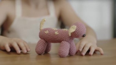 Child playing with handmade knitted animal shaped toy. Close-up of child's hands and knitted handmade toy. Soft knitted toy made of crochet yarn.