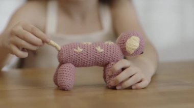 Child playing with handmade knitted animal shaped toy. Close-up of child's hands and knitted handmade toy. Soft knitted toy made of crochet yarn.