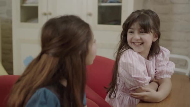 Μικρά Όμορφα Και Χαριτωμένα Κορίτσια Στα Λευκά Κάθονται Στο Τραπέζι — Αρχείο Βίντεο