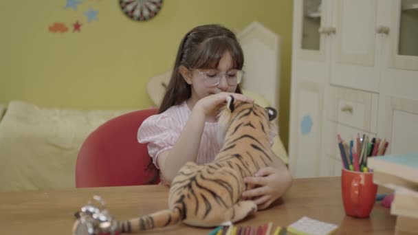 小女孩正在和一只玩具老虎玩耍 一个人在家 没有朋友和玩具老虎玩耍的小女孩 孩子手里拿着棕色玩具老虎 小孩子在客厅里玩玩具老虎 — 图库视频影像