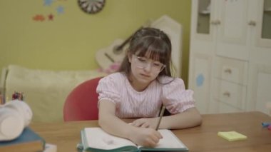 Smart elementary school girl learning to write, doing math homework, sitting at home desk. Portrait of a little boy having a coughing fit doing school homework.