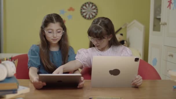 ホーム保育園でタブレットコンピュータを使用してオンラインゲームをプレイする2人の女の子の友人 子供のインターネット中毒 タブレット上のコンピュータでゲームをプレイする女の子の肖像画 — ストック動画