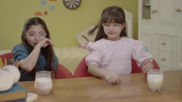 おやつ休憩 学校の宿題をしている少女たちは牛乳を飲んでいる 子供の健康的な食事の肖像画 — ストック動画