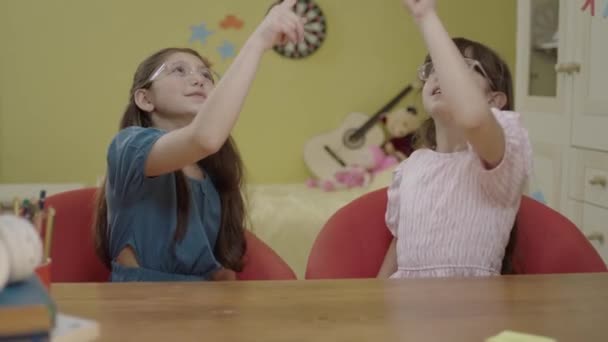Little Cute Girls Sitting Table Nursery Pointing Fingers Advertising Space — Vídeo de Stock
