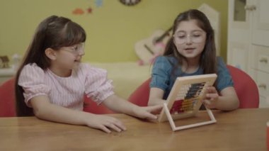 Girls playing with cute little abacus. Children playing with wooden abacus at home. Kids having fun with educational preschool toy.