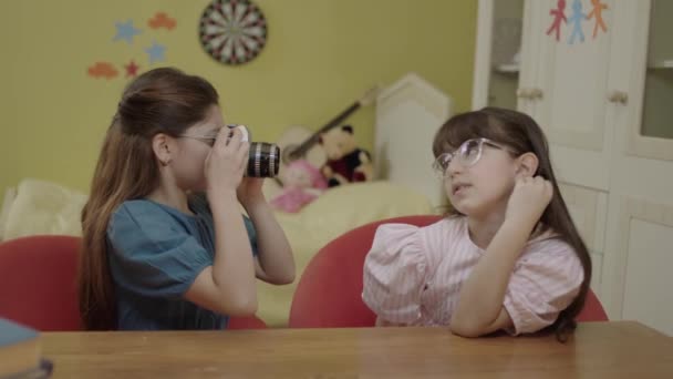 漂亮可爱的小女孩们坐在托儿所的桌子边 互相拍照 有爱心的女孩坐在幸福的家的扶手椅上 一边聊天一边笑 — 图库视频影像
