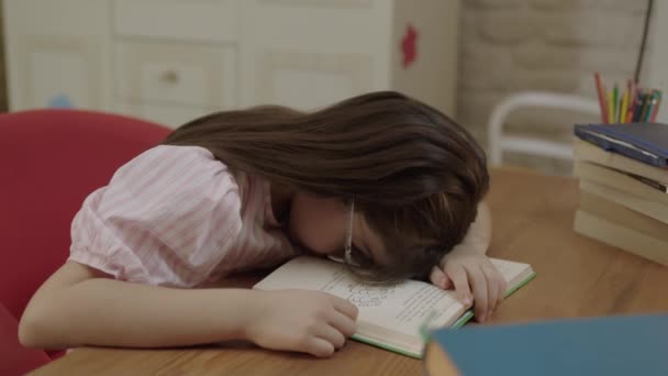 疲れて小さな女の子の学校の仕事に疲れて 本の中で問題を解決する 退屈な感じを勉強女子高生 数学のレッスンを行うの疲れています 疲労の屋内ショットと過労の女の子はテーブルで本の上で寝て — ストック動画