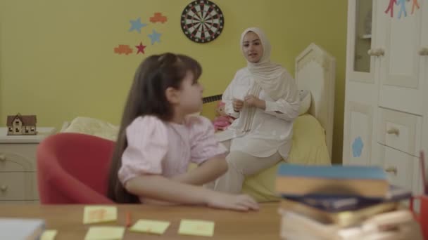 Otthon Kislány Asztalnál Felsorolja Kis Színes Papírokat Hidzsáb Anya Figyelmezteti — Stock videók