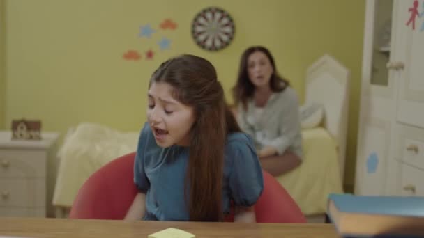 집에서 소녀는 탁자에 앉아서 종이에 어머니는 딸에게 숙제를 하라고 소녀는 — 비디오