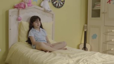 Dramatic portrait of little girl with sad face sitting on her bed.Bored girl at home. Dramatic portrait of little girl with sad face sitting on her bed. Lonely boy with no friends.