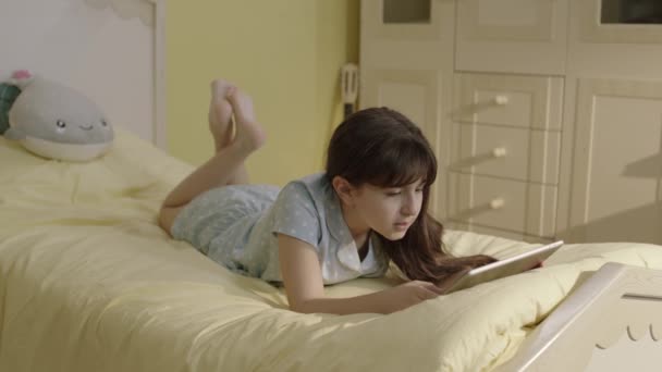 Little Girl Surfing Internet Tablet Computer Lying Her Bed Home — Video Stock