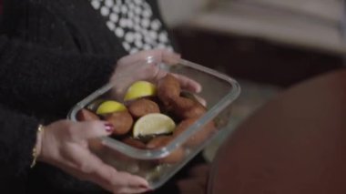 The hands of the woman who puts the stuffed meatballs (Icli Kofte) on the dinner table with her gold braceleted arms. Traditional Turkish dishes, meatballs, ground beef and bulgur.