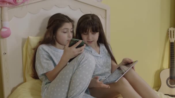 孩子们正在用技术交流工具 电话和平板电脑上网 女孩在床上听在线课程 看视频 玩游戏 — 图库视频影像