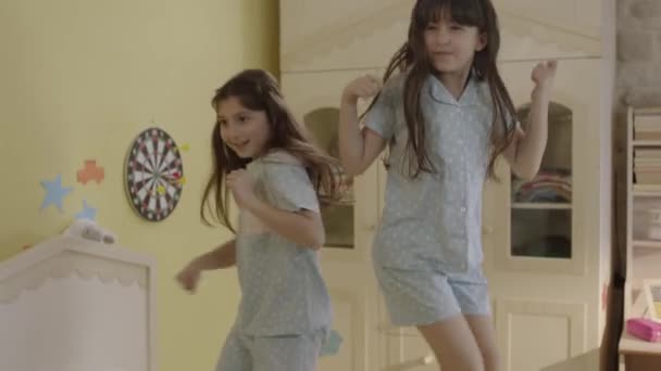 Две Маленькие Девочки Пижаме Веселятся Прыгая Кровати Весёлые Милые Счастливые — стоковое видео