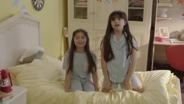 Δύο Κοριτσάκια Πιτζάμες Διασκεδάζουν Πηδώντας Στο Κρεβάτι Διασκέδαση Χαριτωμένο Ευτυχισμένη — Αρχείο Βίντεο