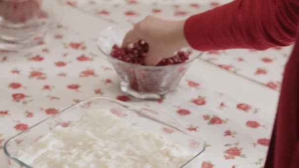 ラマダーン中にイスラム教徒によって作られた牛乳とザクロとガラスのデザート 台所のテーブルの上に甘草の上にザクロの種を投げる女性のクローズアップ手 オスマン料理のデザート — ストック動画