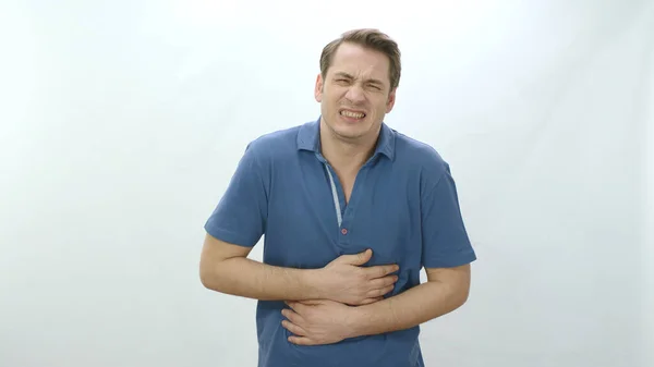 Sick, unhealthy heart and man with painful cramp in his stomach is squeezing his stomach and suffering from severe heart pain.Man in his 30s strong chest pain,heart attack caused by stress,cardiology.