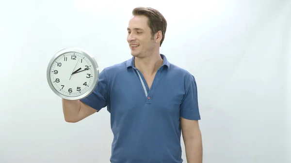 Character portrait of young man holding a large wall clock and looking at the empty advertising space to the left of the screen. The man shows that time passes and it is necessary to use time well.