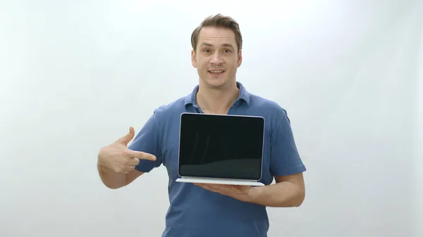 Isolated young man holding a laptop on white background. Young man pointing with finger inside laptop. Creative people can put whatever they want in advertising spaces.