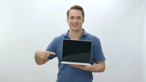 Isolated young man holding a laptop on white background. Young man pointing with finger inside laptop. Creative people can put whatever they want in advertising spaces.