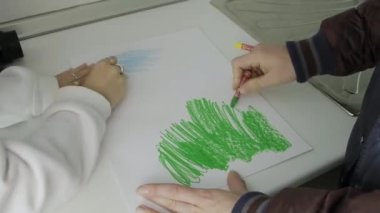 Hands painting a white page with colored crayons.Drawing ideas with crayons. Child development concept.