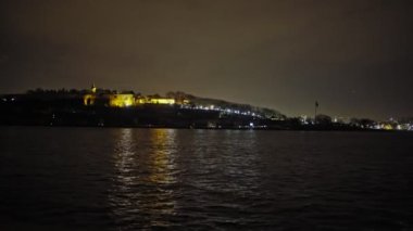 The sea where the yellow lights of the city are reflected.A view of Istanbul in the summer night. Topkapi Palace view from the sea.Night sea sparkles bright light water moonlight.