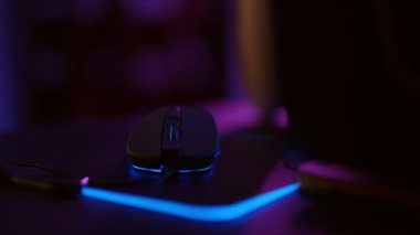 Close-up hands of gamer playing video game using illuminated mouse.Male hand using mouse. Background with neon lights.