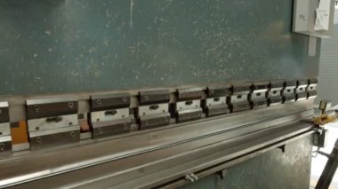Operator bends a sheet of metal on a bending machine.Bending sheet metal. Worker cuts and bends a metal sheet on an industrial machine. CNC-controlled sheet metal bending machine in a factory.
