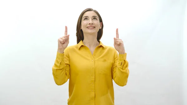 Woman pointing to the top of the screen, finger pointing at the advertising space above the screen, isolated on a white background. Creative people can put anything they want where they show.