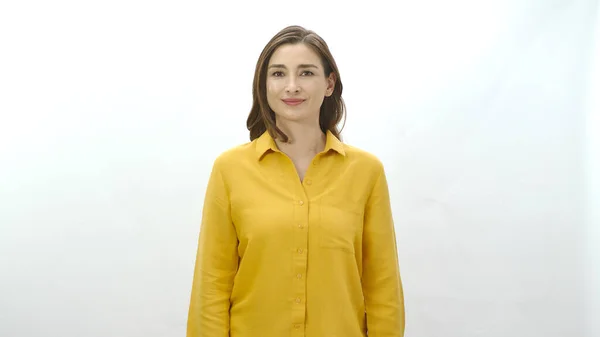 女人笑着看着白色背景上的相机 穿着黄色衬衫的漂亮女人的画像 — 图库照片