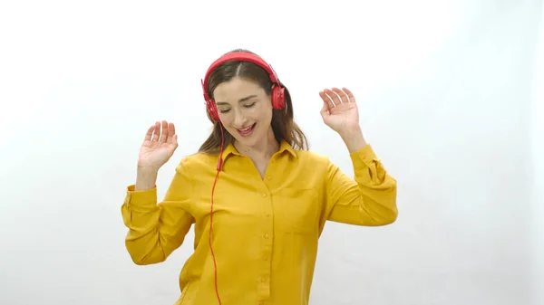 白い背景にヘッドフォンで隔離された女性の歌 赤いヘッドフォンで音楽を聴きながら踊る女性 恋の女の肖像 — ストック写真
