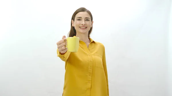 Character portrait of a young woman drinking a cup of coffee, black or green tea. Young healthy woman pointing at camera with cup of coffee or tea isolated on white background.