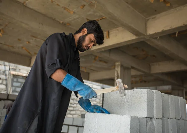 İnşaat işçisi çalışma zamanında inşaat binasında çekiç kullanarak beton tuğla kırmış. Sıkı çalışma kavramı.