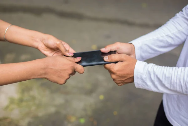 Mobil bağımlılık kavramı. Bir cep telefonu ya da akıllı telefon için kavga eden hoşnutsuz öğrencilerin fotoğrafı. Mobil bağımlılığın yakın çekim görüntüsü