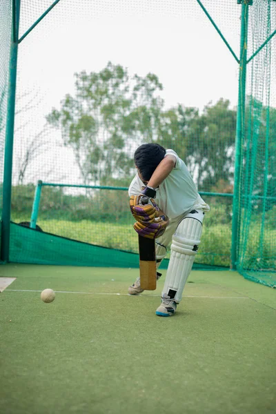 Cricket Batsman Action 'ın ön görüntüsü, kriket maçı yakın plan oyuncusu net antrenman sırasında topa vuruyor. Odaklanmış vurucu antrenman sırasında topa vuruyor.