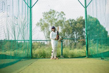 Cricket Batsman bowlingci için bekliyor. Oyuncu ağlarda daha fazla pratik yapmaya hazır. Odaklanmış oyuncu oynamaya hazır, yüksek kalite fotoğraf. 