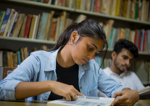 Genç üniversite öğrencileri yaklaşan sınavları için üniversite kütüphanesinde okuyor. Öğrenciler yaklaşan sınavlar için çalışıyor. Ana odak noktamız kız..