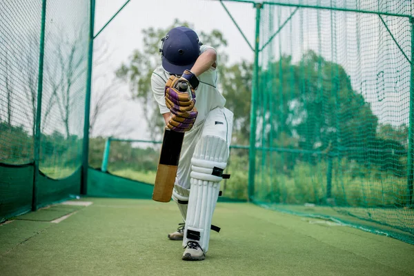 Cricket Batsman Action 'ın ön görüntüsü, kriket maçı yakın plan oyuncusu net antrenman sırasında topa vuruyor. Odaklanmış vurucu antrenman sırasında topa vuruyor.
